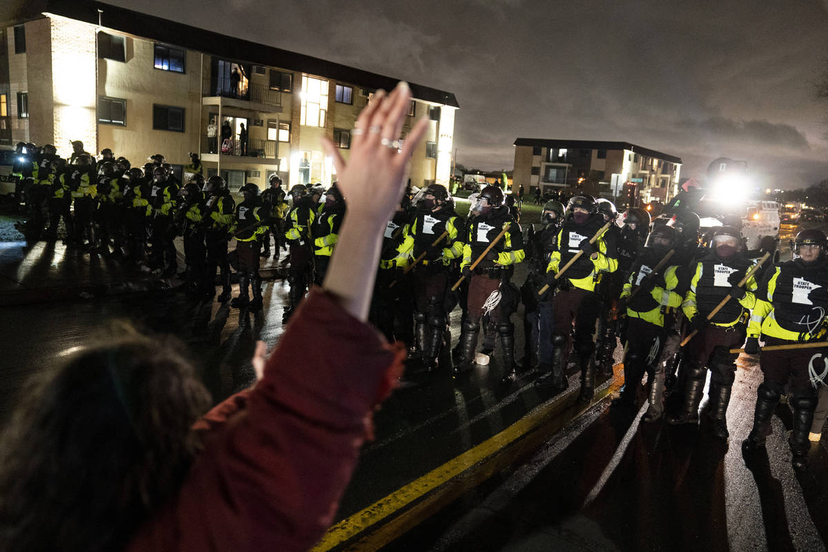 Un manifestante levanta la mano mientras se enfrenta a un perímetro de policías mientras desa ...