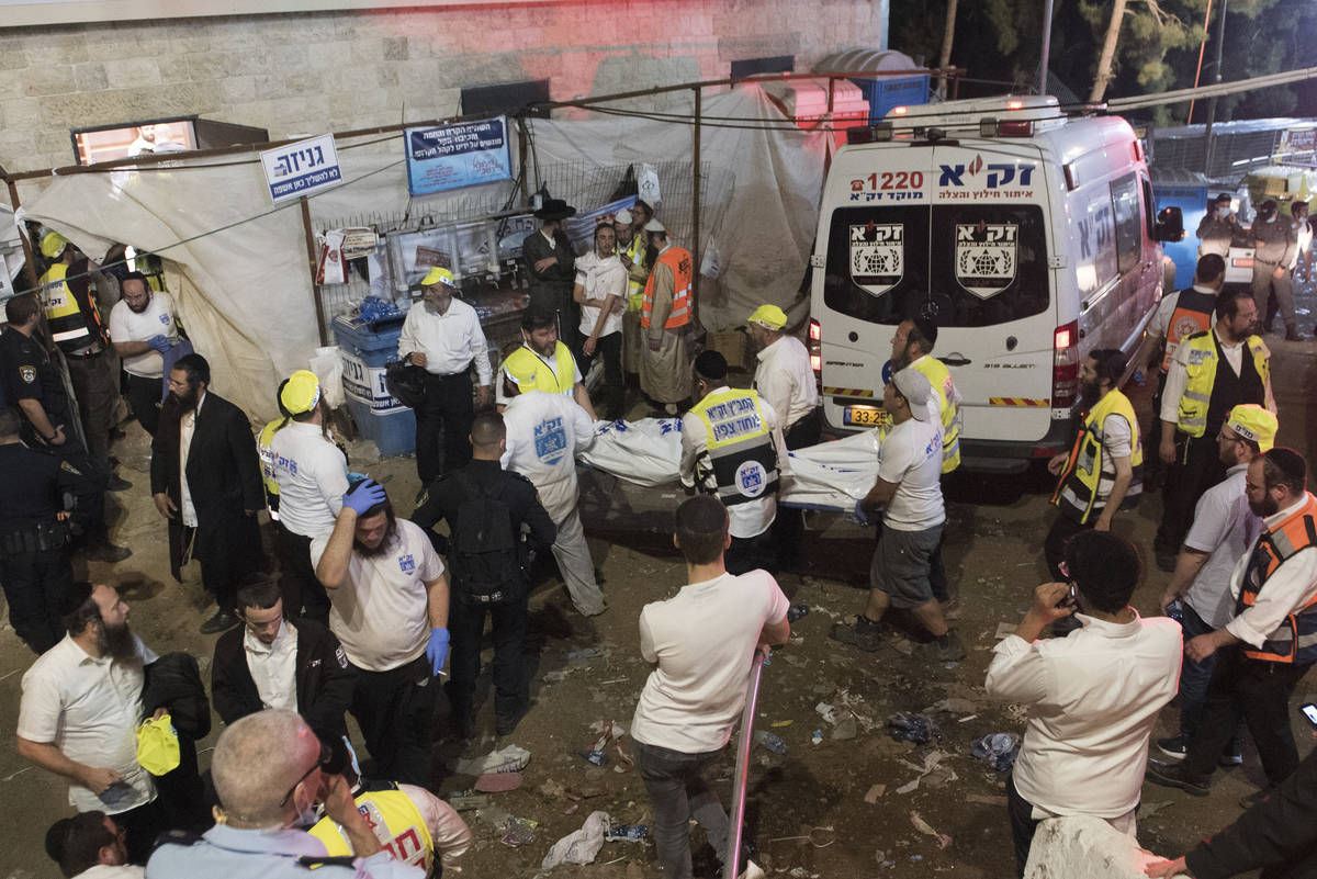 Funcionarios de seguridad israelíes y rescatistas llevan el cuerpo de una víctima que murió ...