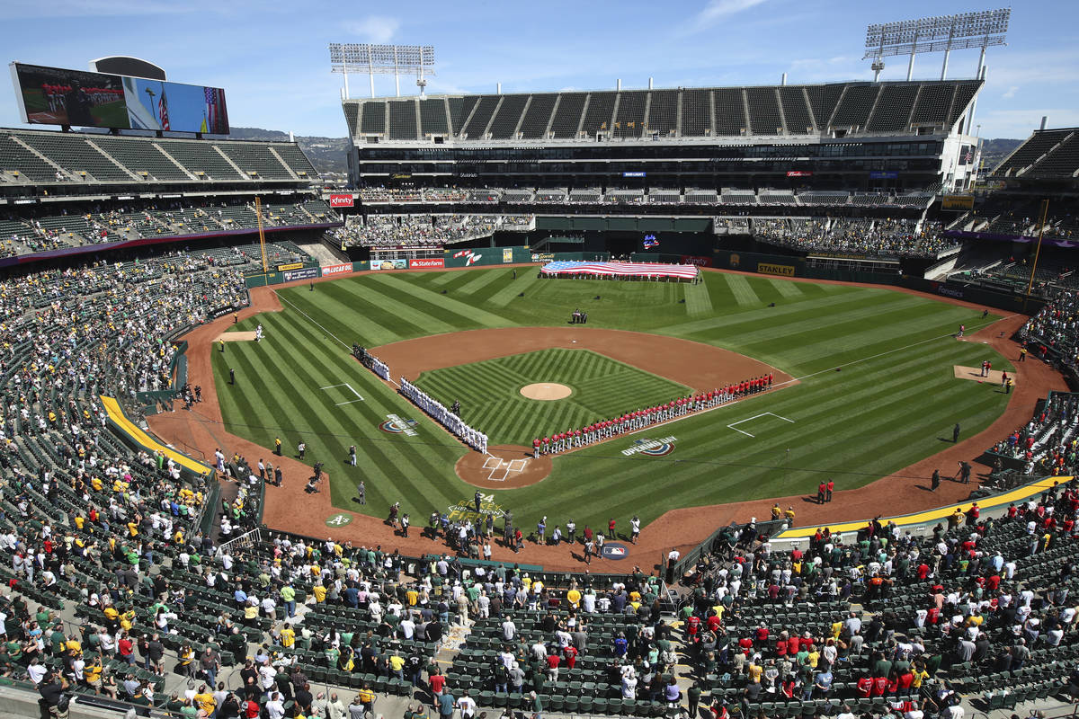 Los Los Angeles Angels y Oakland Athletics se paran para el himno nacional en el Oakland Colise ...