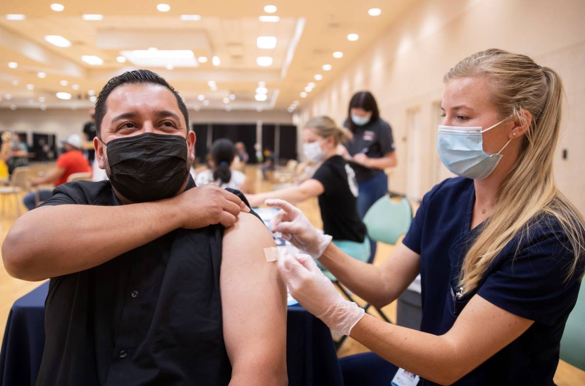 José Padilla, a la izquierda, recibe su vacuna contra COVID-19 de la estudiante de asistente m ...