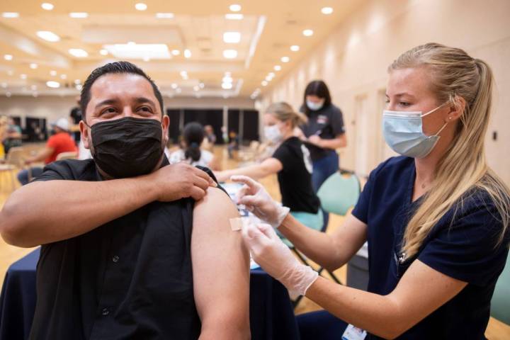 José Padilla, a la izquierda, recibe su vacuna contra COVID-19 de la estudiante de asistente m ...