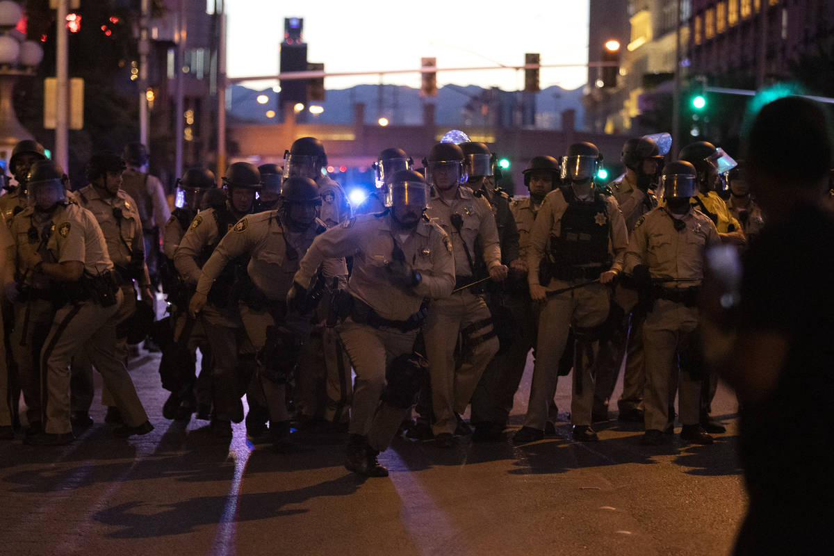 Agentes de policía de Las Vegas corren hacia la multitud de manifestantes que tomaron el Strip ...