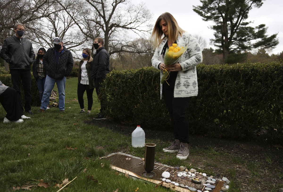 Michelle Pepe coloca un ramo de rosas amarillas en la tumba de su padre mientras sus familiares ...
