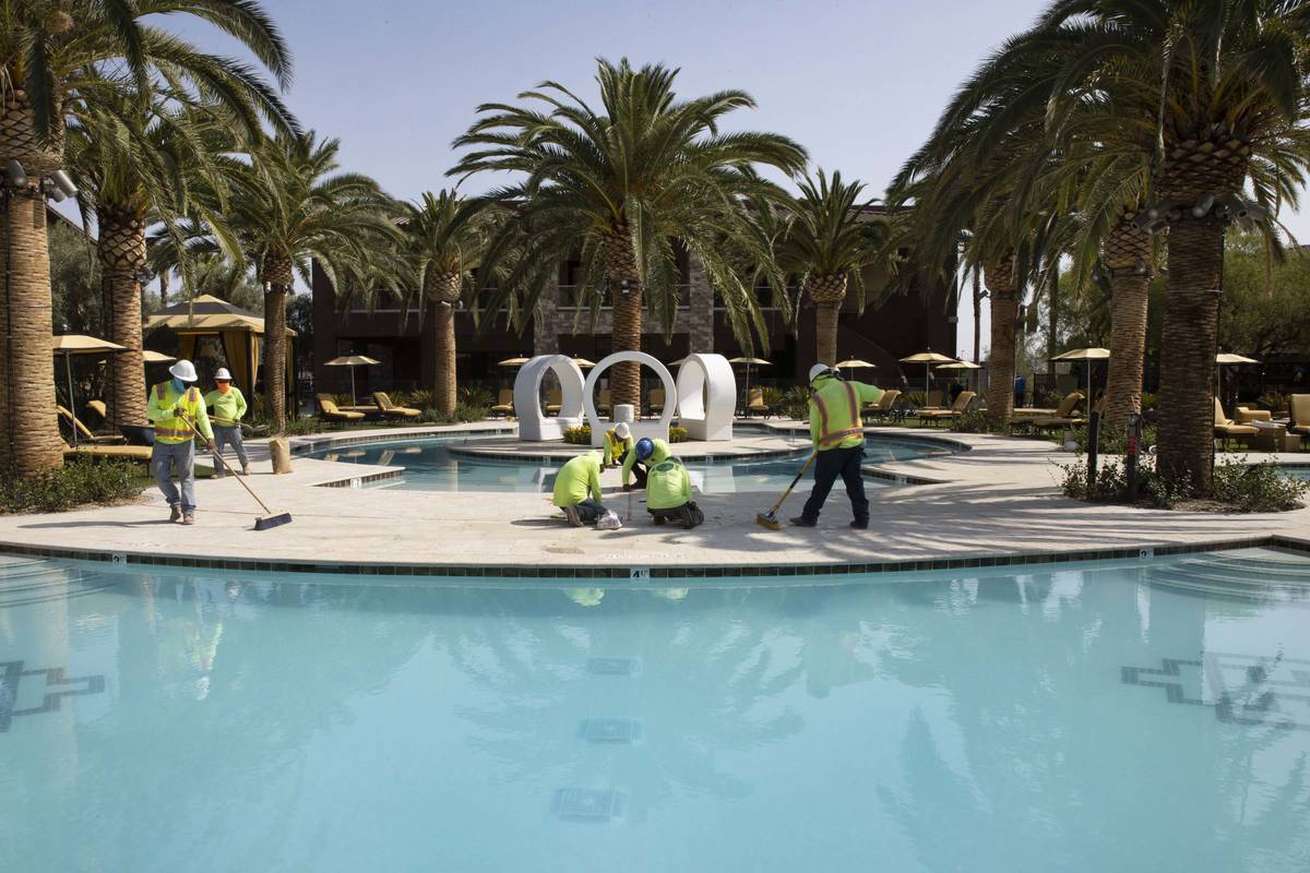 Equipos trabajan en el área de piscina del complejo de apartamentos Tuscan Highlands en constr ...