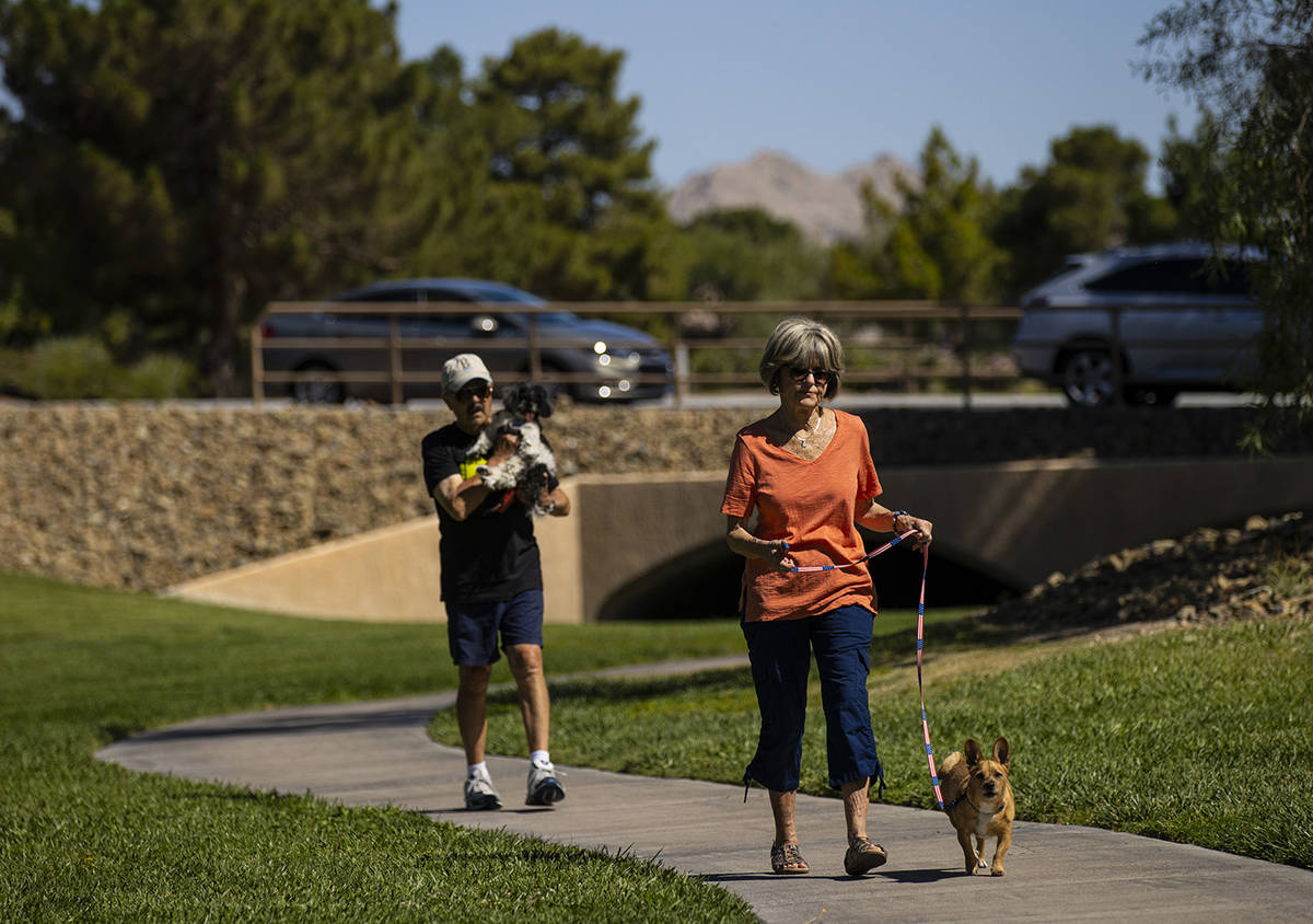 Carol Liberty pasea a su perro, Mikey, mientras Phil Sardo, llevando a su perro, Mei Mei, camin ...