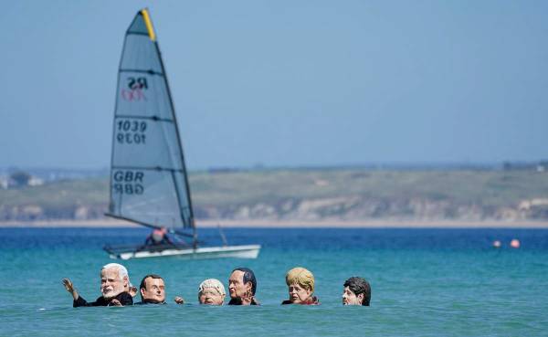Manifestantes con cabezas gigantes que representan a los líderes del G7 nadan en el agua duran ...
