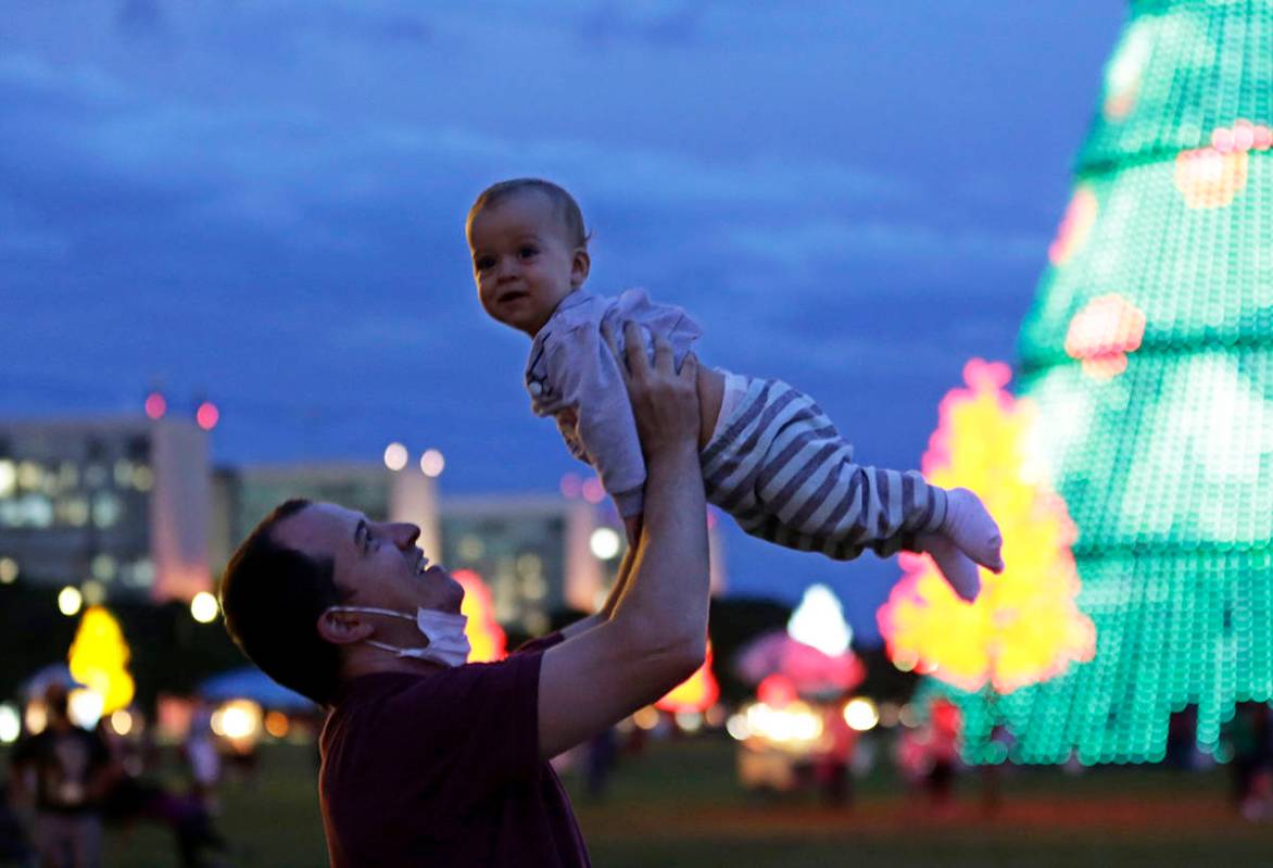 En esta foto de archivo, un padre con su cubrebocas hacia abajo, juega con su hijo en la Explan ...