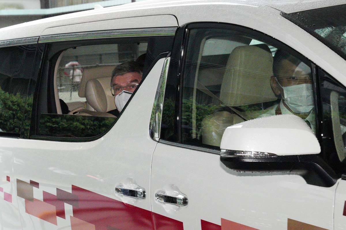 El presidente del Comité Olímpico Internacional, Thomas Bach, saluda desde el vehículo a los ...