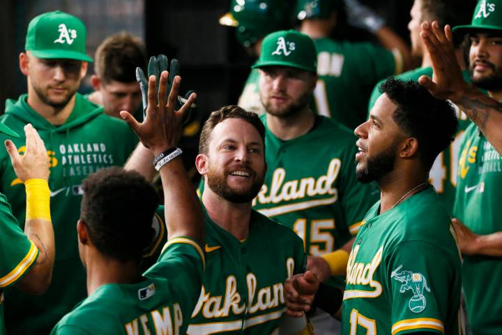 Jed Lowrie, de los Oakland Athletics, es saludado en el dugout después de batear un jonrón co ...