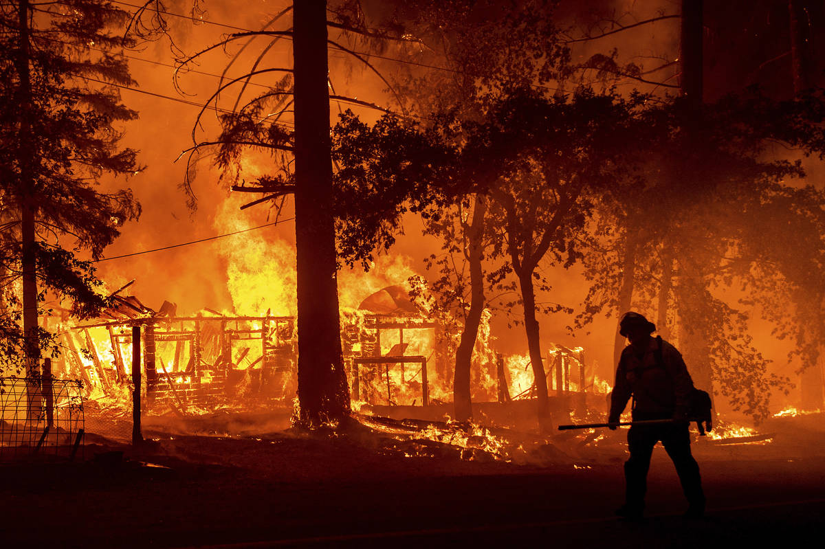 Un bombero pasa por delante de una casa en llamas mientras el Dixie Fire incendia el Condado Pl ...