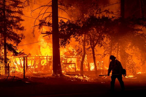 Un bombero pasa por delante de una casa en llamas mientras el Dixie Fire incendia el Condado Pl ...