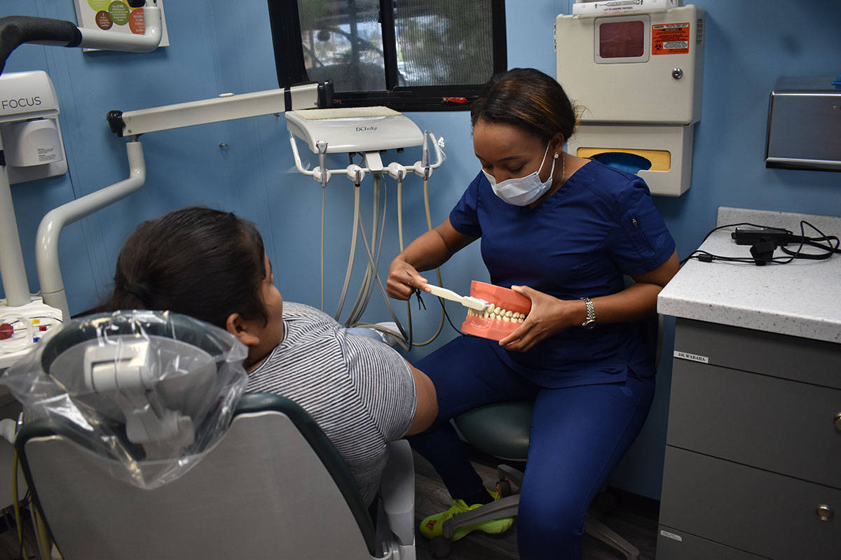 La dentista Alexandra Wabara le enseña a Jaqueline Silva cómo debe de cepillarse los dientes ...