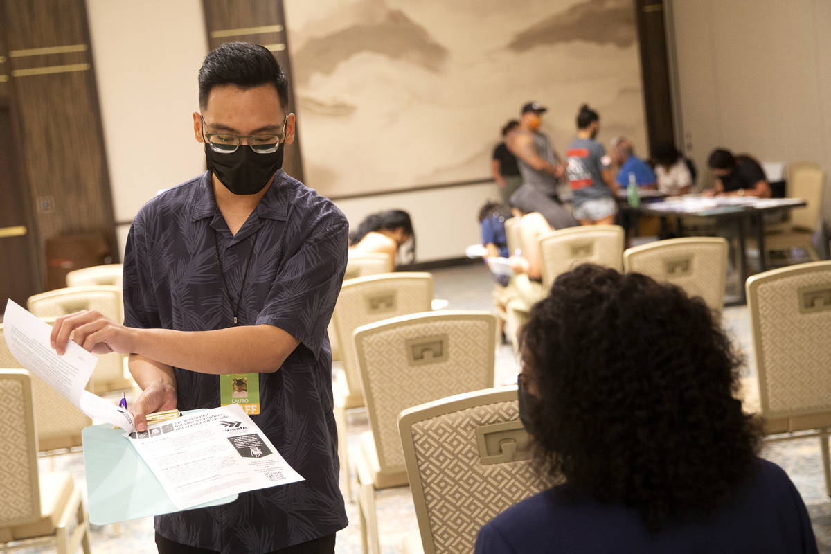 Lauro Solomo, trabajadora de salud comunitaria de Immunize Nevada, comparte el papeleo con Jess ...