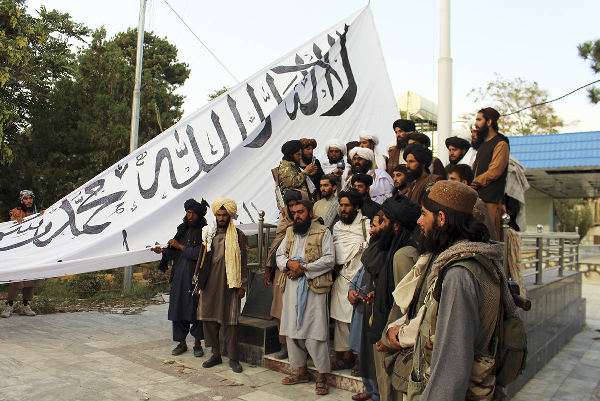 Combatientes talibanes posan para una fotografía mientras izan su bandera en la casa del gober ...