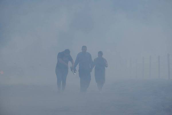 José Lamas y su hija Astrid Covarrubias caminan por el humo y por los restos carbonizados que ...