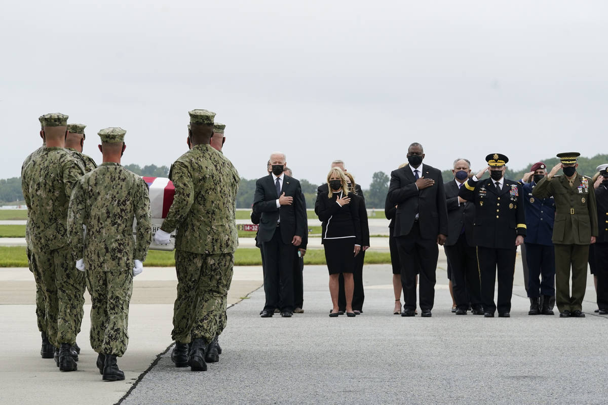 El presidente Joe Biden observa cómo un equipo de transporte de la Marina traslada una caja qu ...