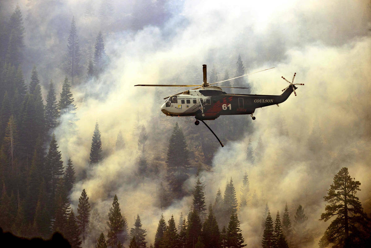 Un helicóptero del Departamento de Bomberos del Condado Ventura vuelve a por más agua para de ...
