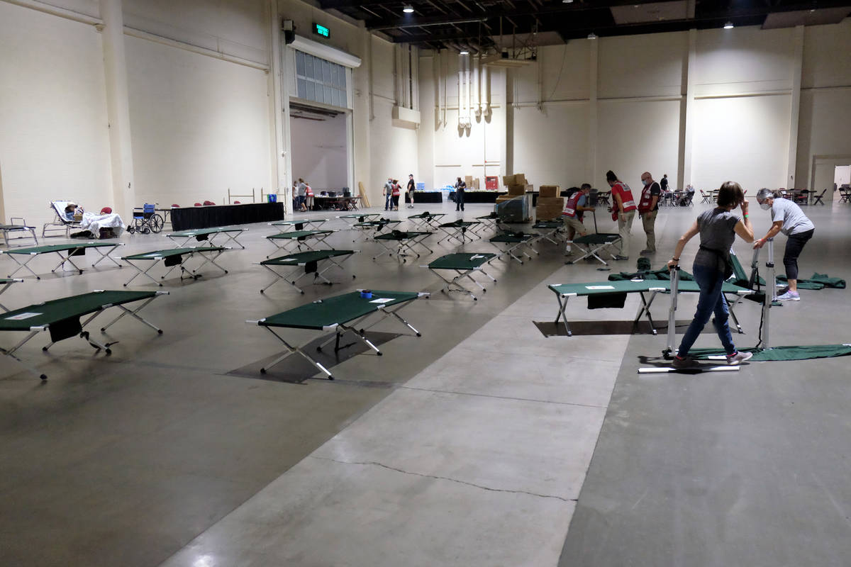 Trabajadores y voluntarios de la Cruz Roja instalan catres en un centro de evacuación para per ...