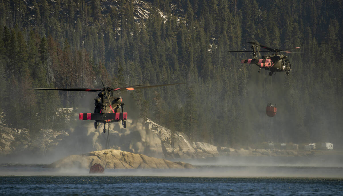 Los helicópteros recogen agua de Silver Lake para dejarla caer en una cresta cercana mientras ...