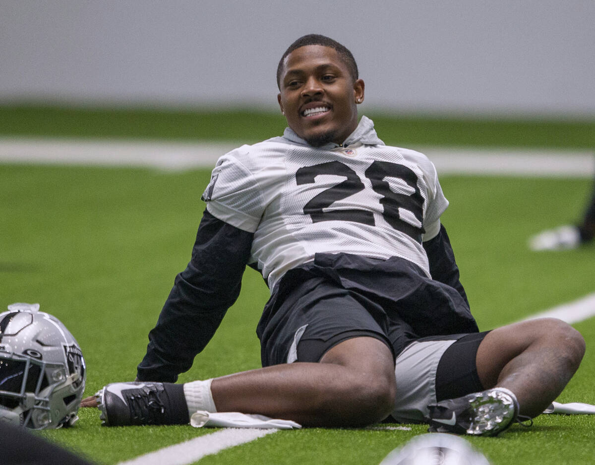 El running back de los Raiders Josh Jacobs (28) se ríe mientras estira durante una sesión de ...
