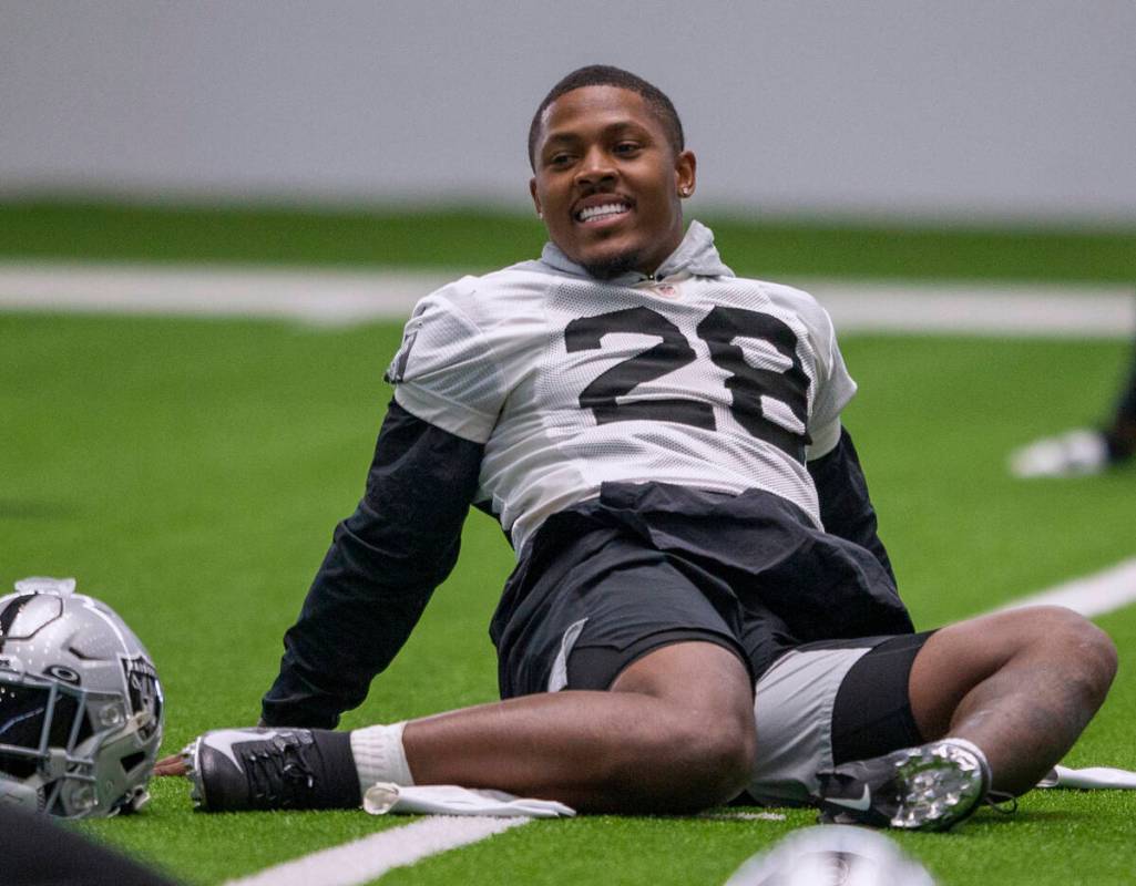 El running back de los Raiders Josh Jacobs (28) se ríe mientras estira durante una sesión de ...