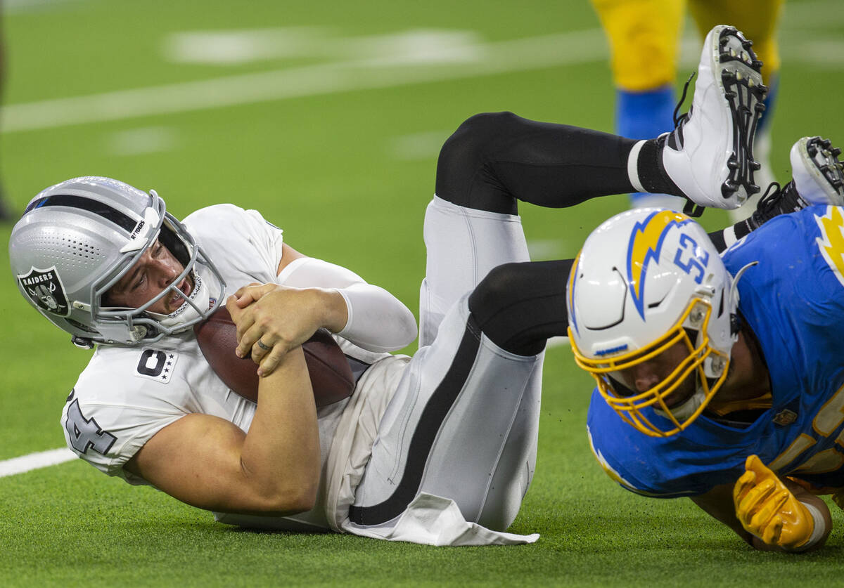 El quarterback de los Raiders, Derek Carr (4), se aferra al balón de fútbol americano despué ...