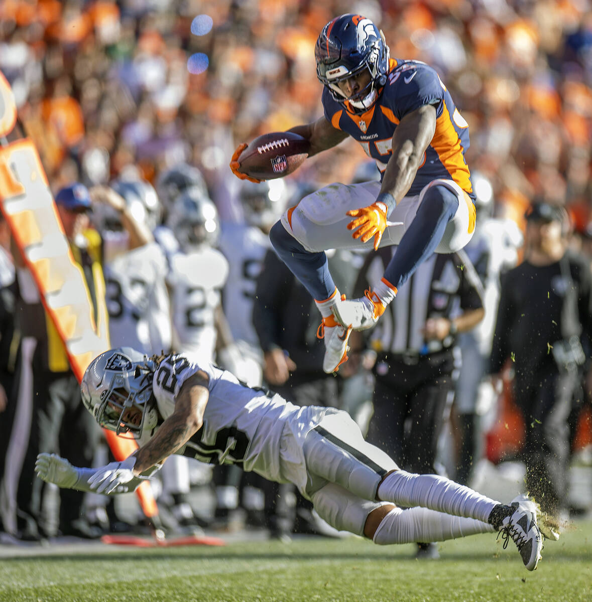 Javonte Williams (33), running back de los Denver Broncos, salta por encima de Trevon Moehrig ( ...