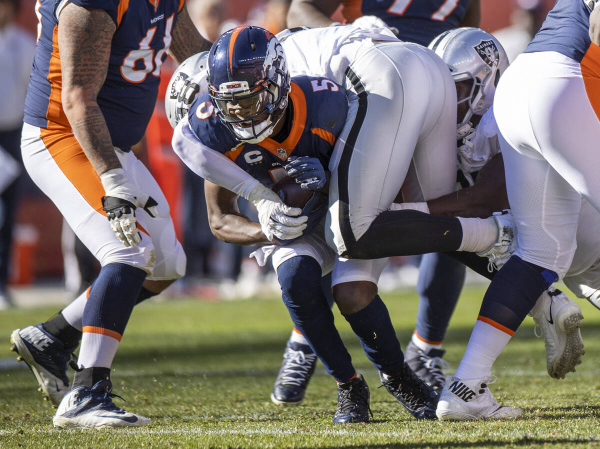 El quarterback de los Denver Broncos, Teddy Bridgewater (5), es tackleado por el defensive end ...