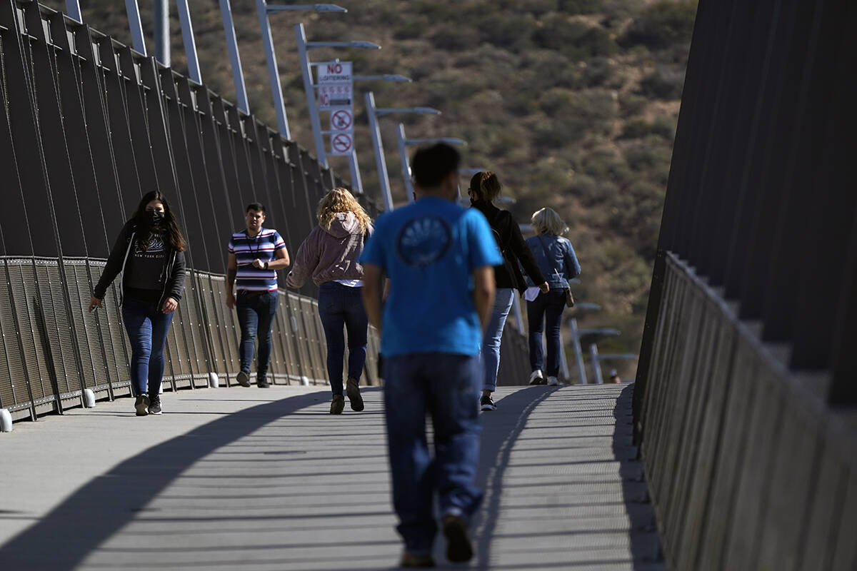 La gente camina sobre un puente en el puerto de entrada de San Ysidro, que conecta Tijuana, Mé ...
