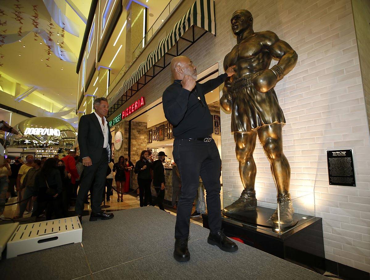 El ex boxeador Mike Tyson, en el centro, posa para fotos frente a la recién inaugurada estatua ...