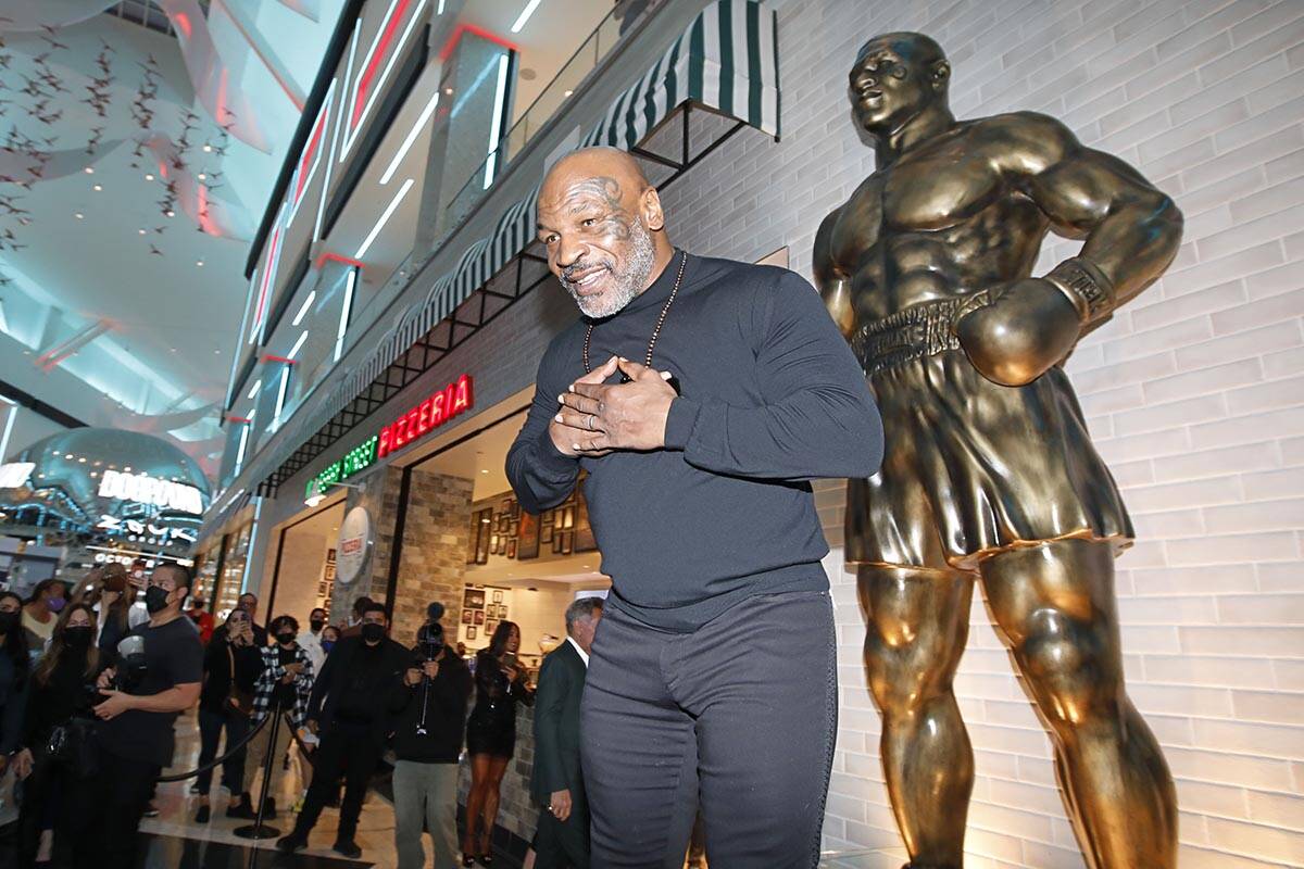 El ex boxeador Mike Tyson, en el centro, posa para fotos frente a la recién inaugurada estatua ...