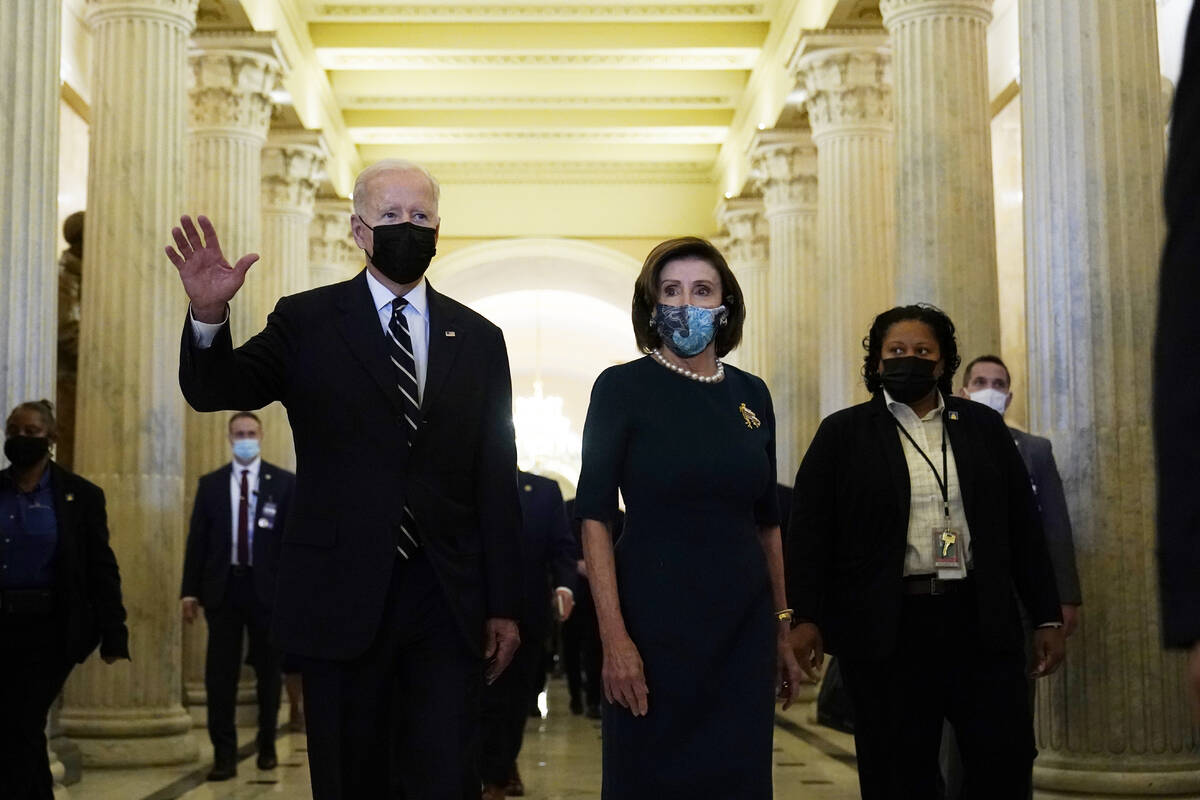 El presidente Biden camina con la presidenta de la Cámara de Representantes, Nancy Pelosi, en ...