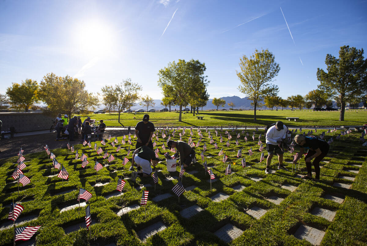 Voluntarios colocan banderas estadounidenses en las tumbas del Southern Nevada Veterans Memoria ...