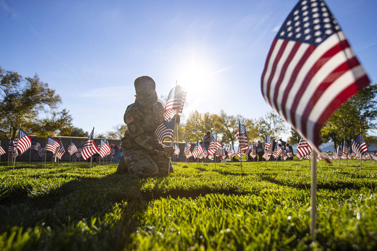 Voluntarios colocan banderas estadounidenses en las tumbas del Southern Nevada Veterans Memoria ...