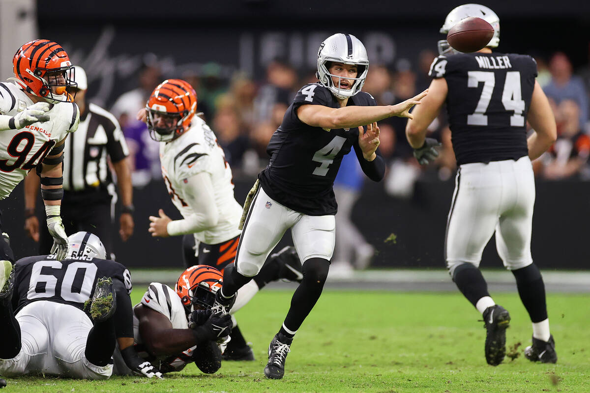 El quarterback de los Raiders, Derek Carr (4), hace un pase bajo la presión del tackle defensi ...