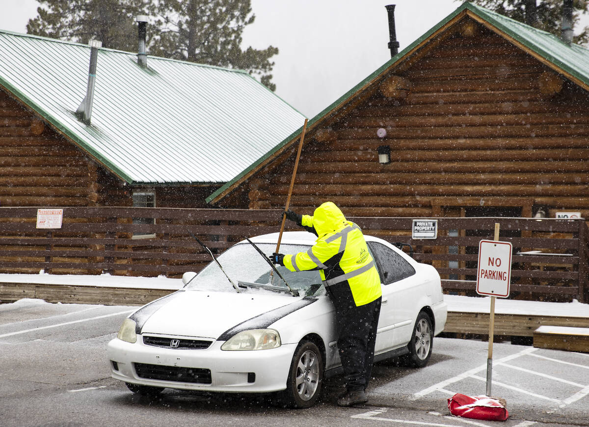 Un trabajador de las cabañas de Mt. Charleston Lodge retira la nieve de un coche estacionado m ...