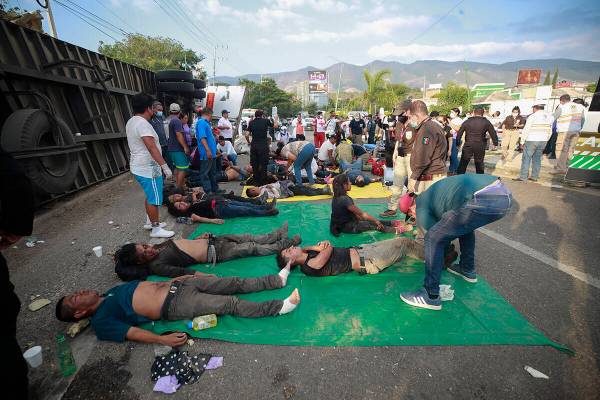 Los migrantes heridos son atendidos al costado de la carretera junto al camión volcado en el q ...