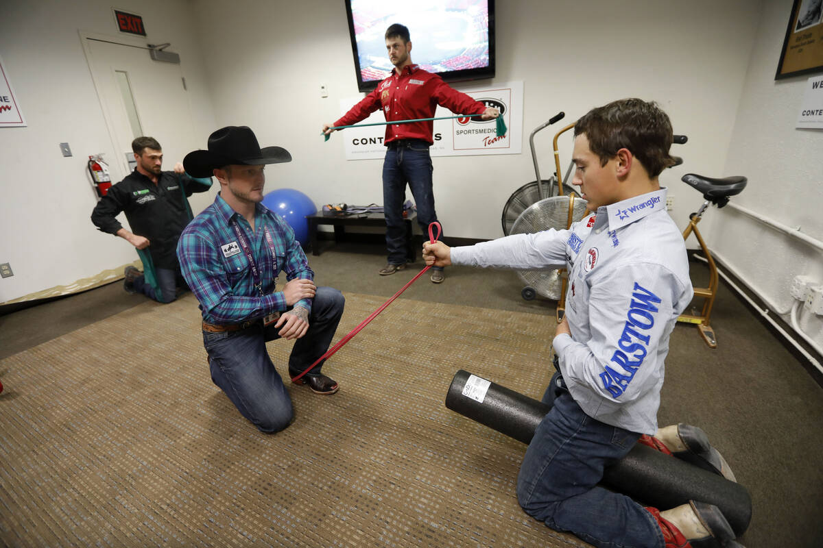 El ex competidor de rodeo Doug Champion, a la izquierda, hace terapia física con el competidor ...