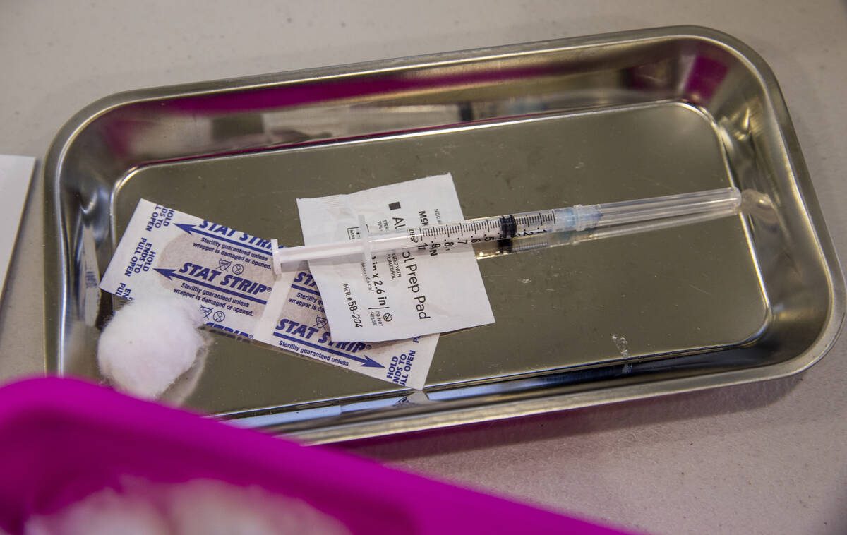 Una inyección se prepara para ser administrada a un cliente en la clínica de vacunación COVI ...