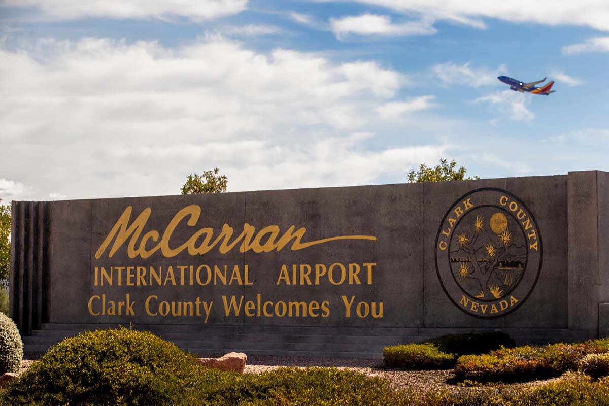 Letrero del Aeropuerto Internacional McCarran con un avión despegando arriba en Tropicana Aven ...