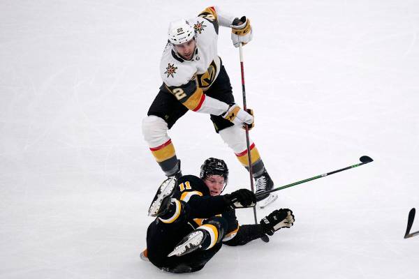 El centro de los Boston Bruins Trent Frederic (11) cae al hielo mientras lucha con el centro de ...