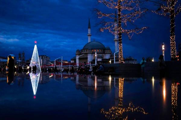 Peatones pasan por delante de un árbol de Navidad junto a la mezquita de Taksim en la plaza de ...