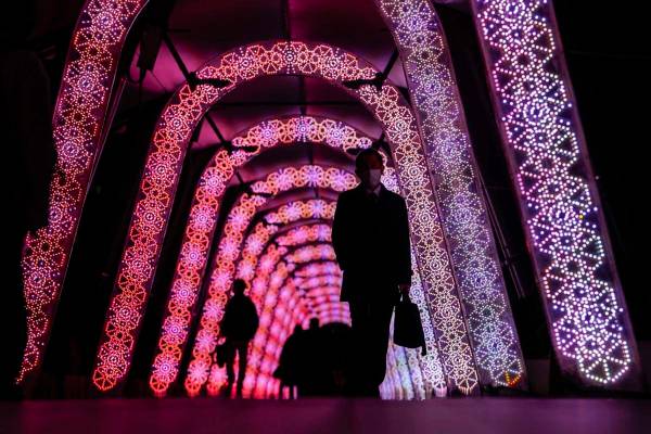 La gente camina a través de un túnel de las exhibiciones de luces navideñas el jueves 9 de d ...