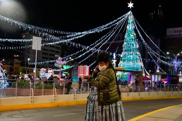 Una mujer aymara habla por su teléfono en la plaza Tejada Sorzano adornada con luces navideña ...