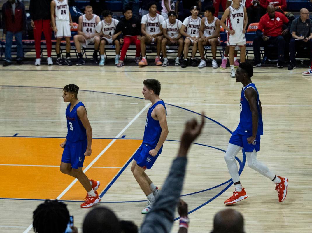 John Mobley Jr. de Bishop Gorman (izquierda) celebra con sus compañeros de equipo después de ...