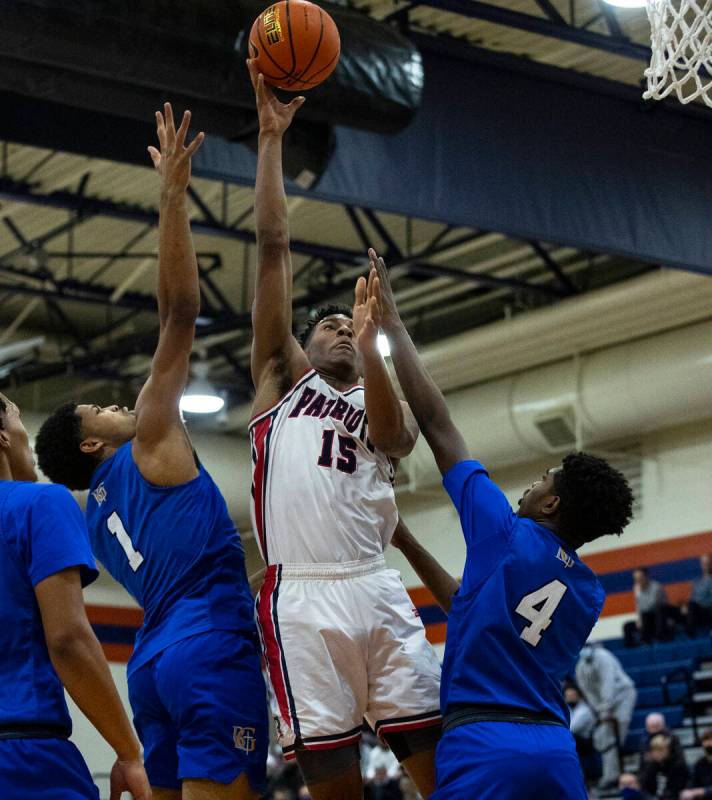 Aaron Price (15), de Liberty High, va hacia el aro entre James Freeman (1) y Jason Richardson ( ...