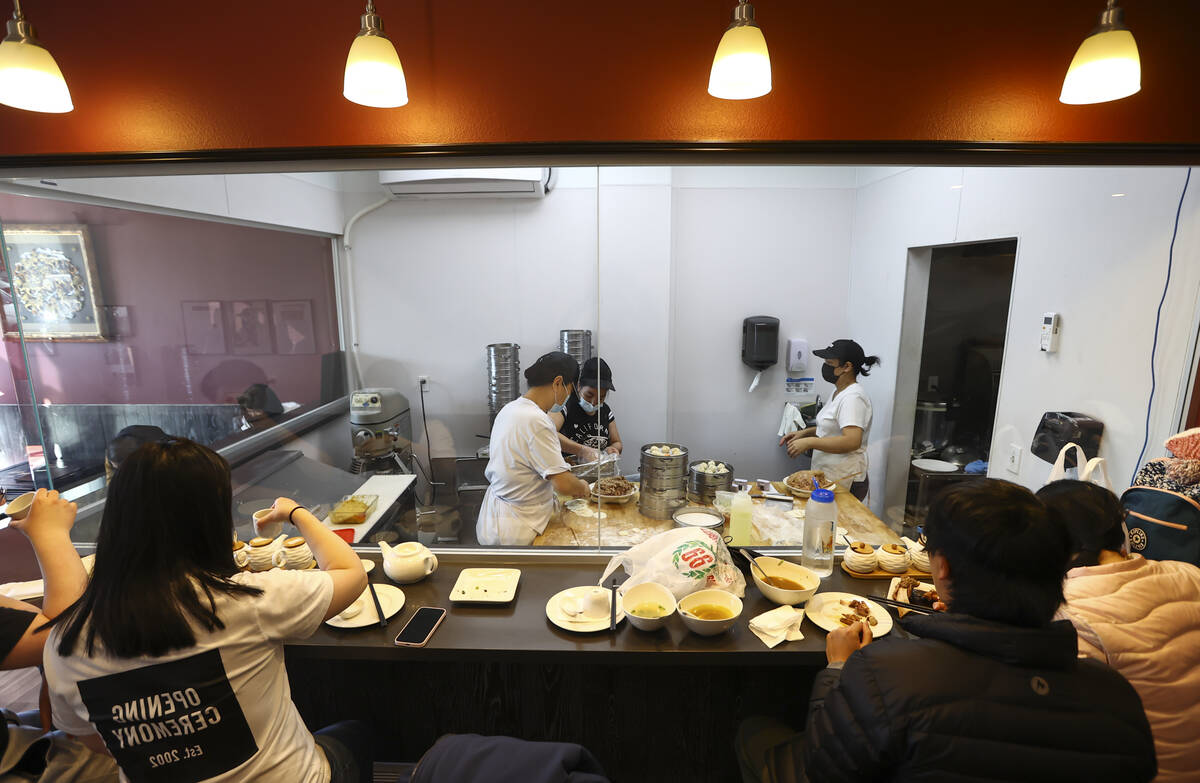 La gente cena mientras los empleados cocinan la comida en el ShangHai Taste en la Plaza Shangai ...