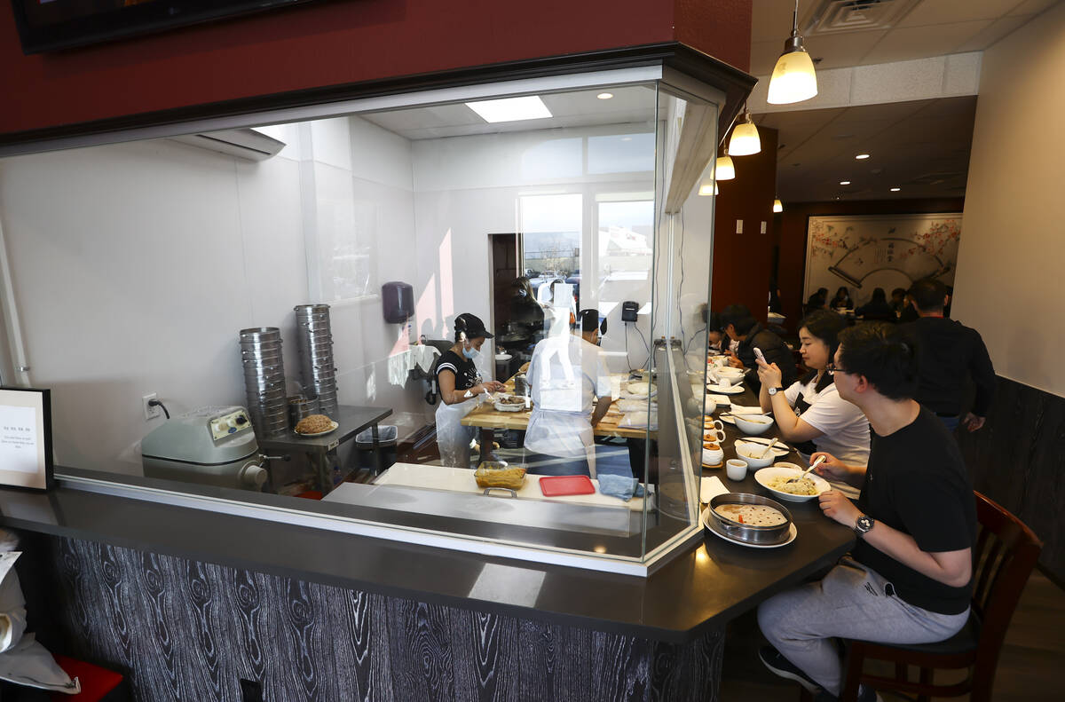 La gente cena mientras los empleados cocinan la comida en el ShangHai Taste en la Plaza Shangai ...