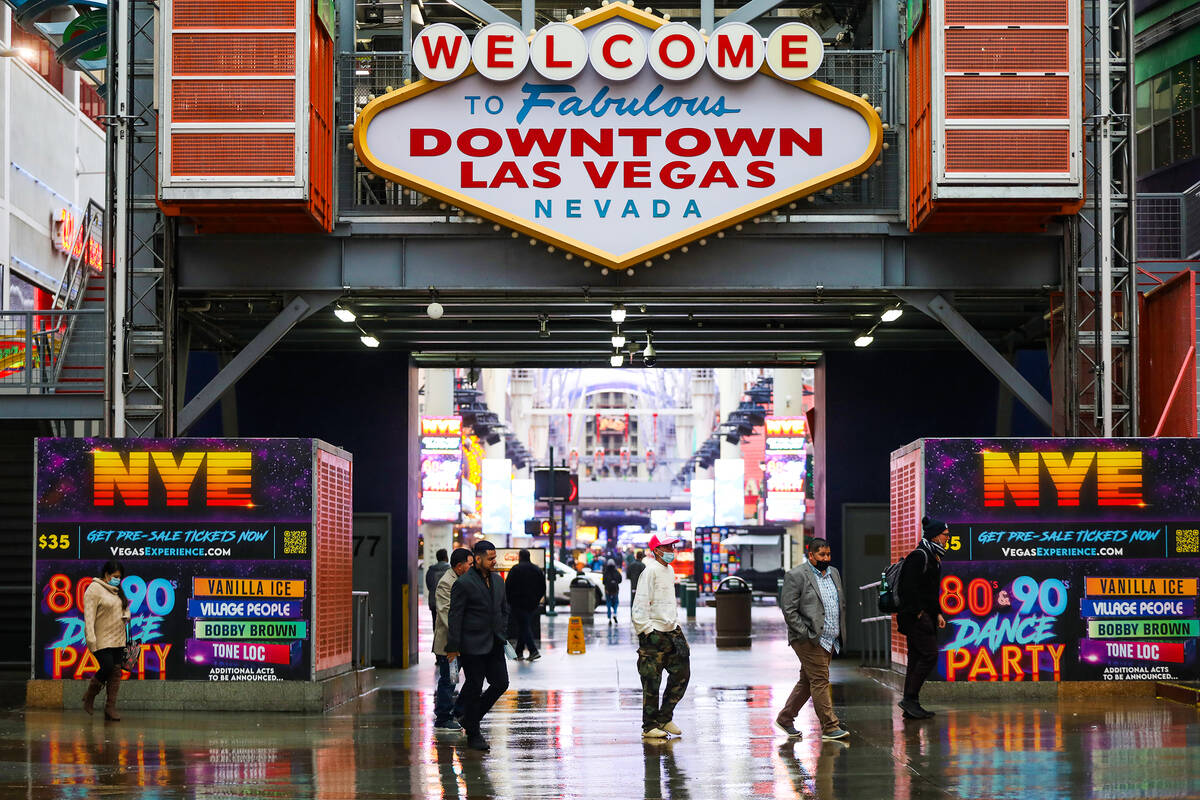Los visitantes caminan bajo la lluvia en la Fremont Street Experience en el centro de Las Vegas ...