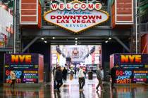 Los visitantes caminan bajo la lluvia en la Fremont Street Experience en el centro de Las Vegas ...